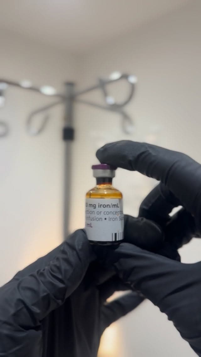 Close-up of an iron infusion vial held in a gloved hand