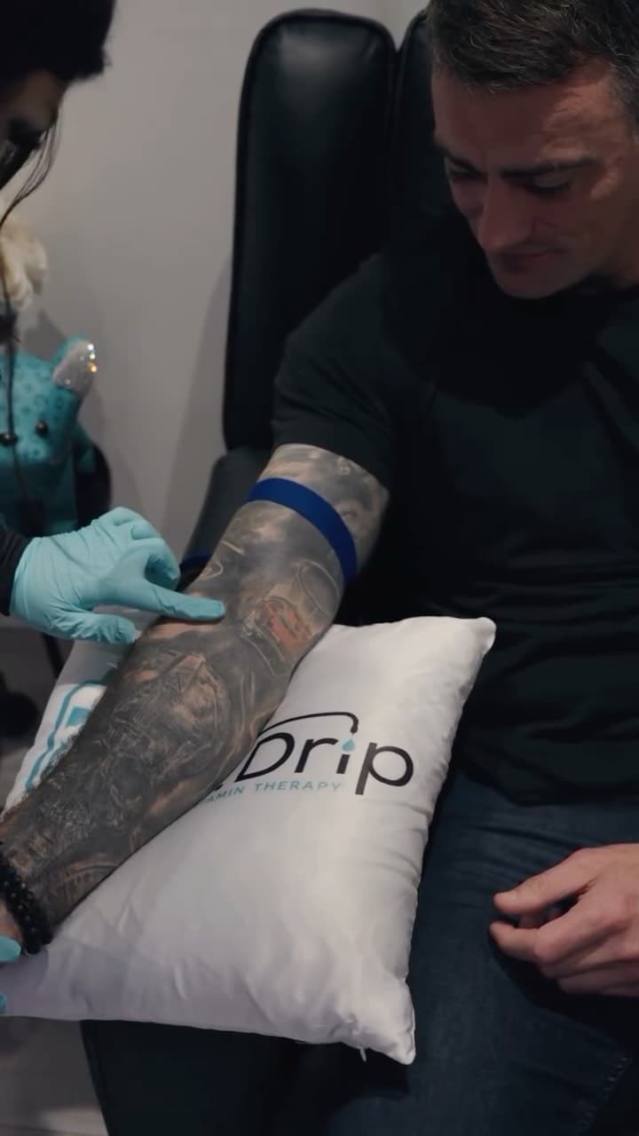 A patient receiving IV therapy at Drip IV, resting on a branded pillow